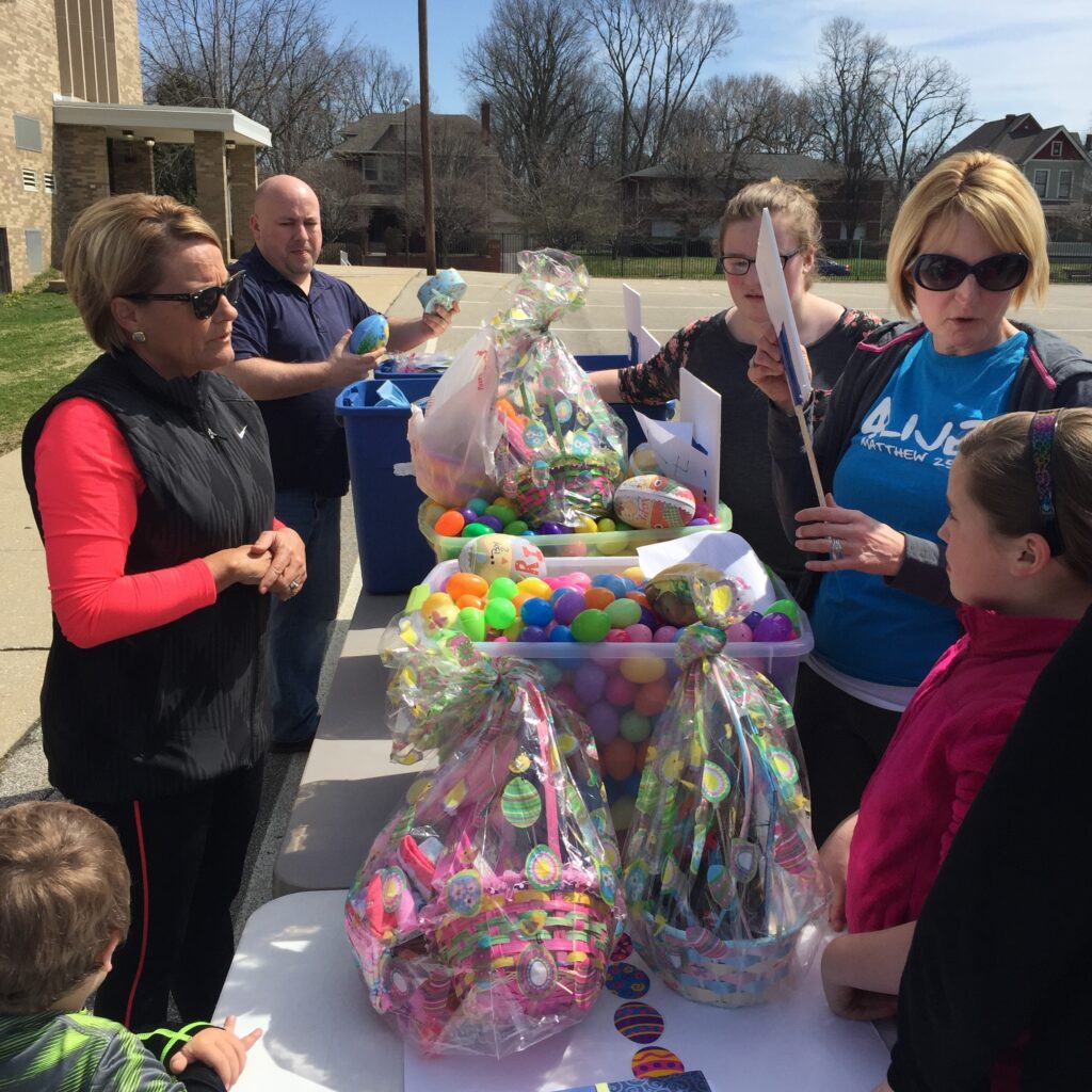 Volunteers and families beside Easter baskets and colorful eggs at CCR Easter.